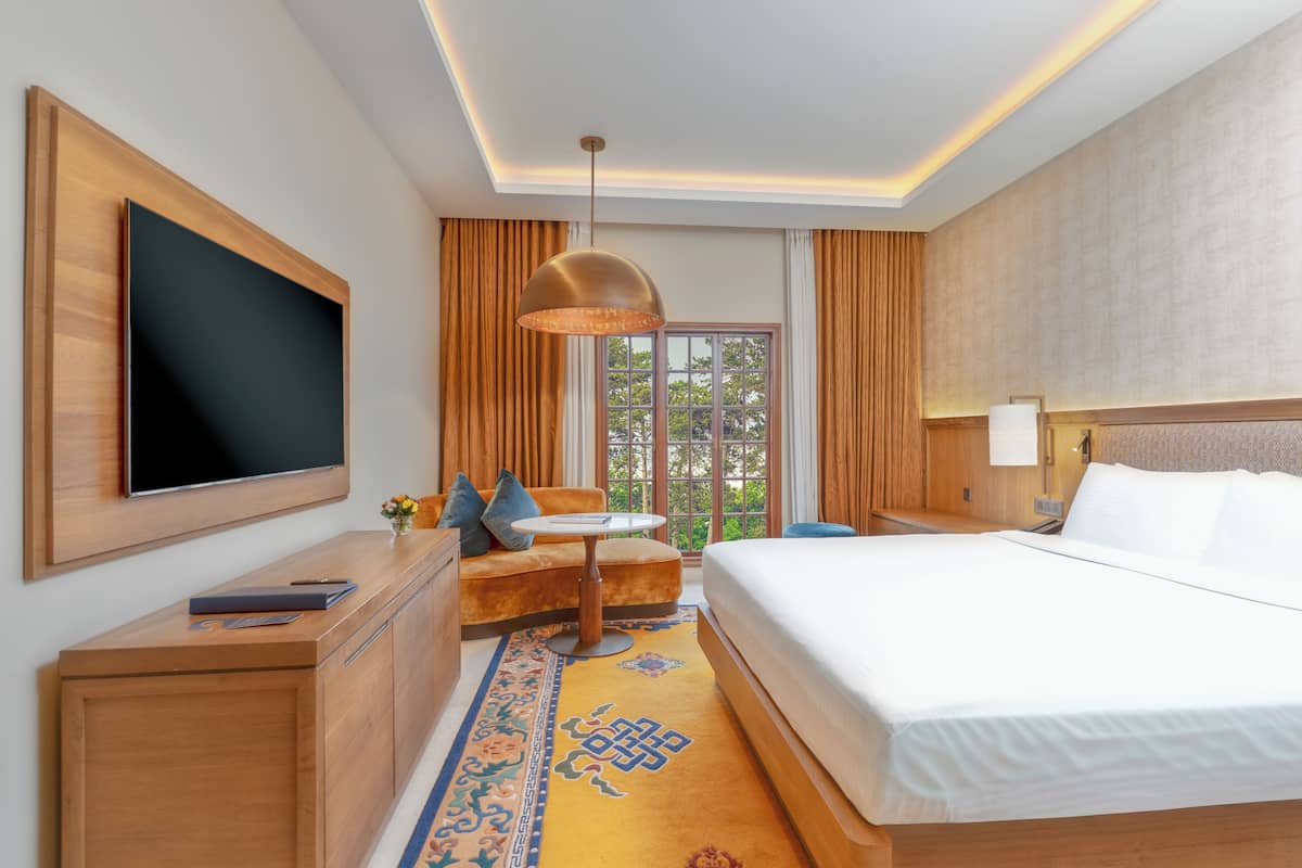 Ein Hotelzimmer mit Bett, Fernseher, Schreibtisch und einem Fenster mit Vorhängen.