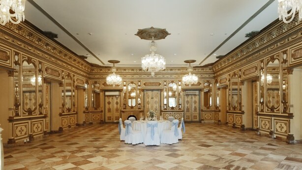 A grand ballroom with ornate gold detailing, a chandelier, and a round table set for a formal event. - Hotel Yak & Yeti (Kathmandu)