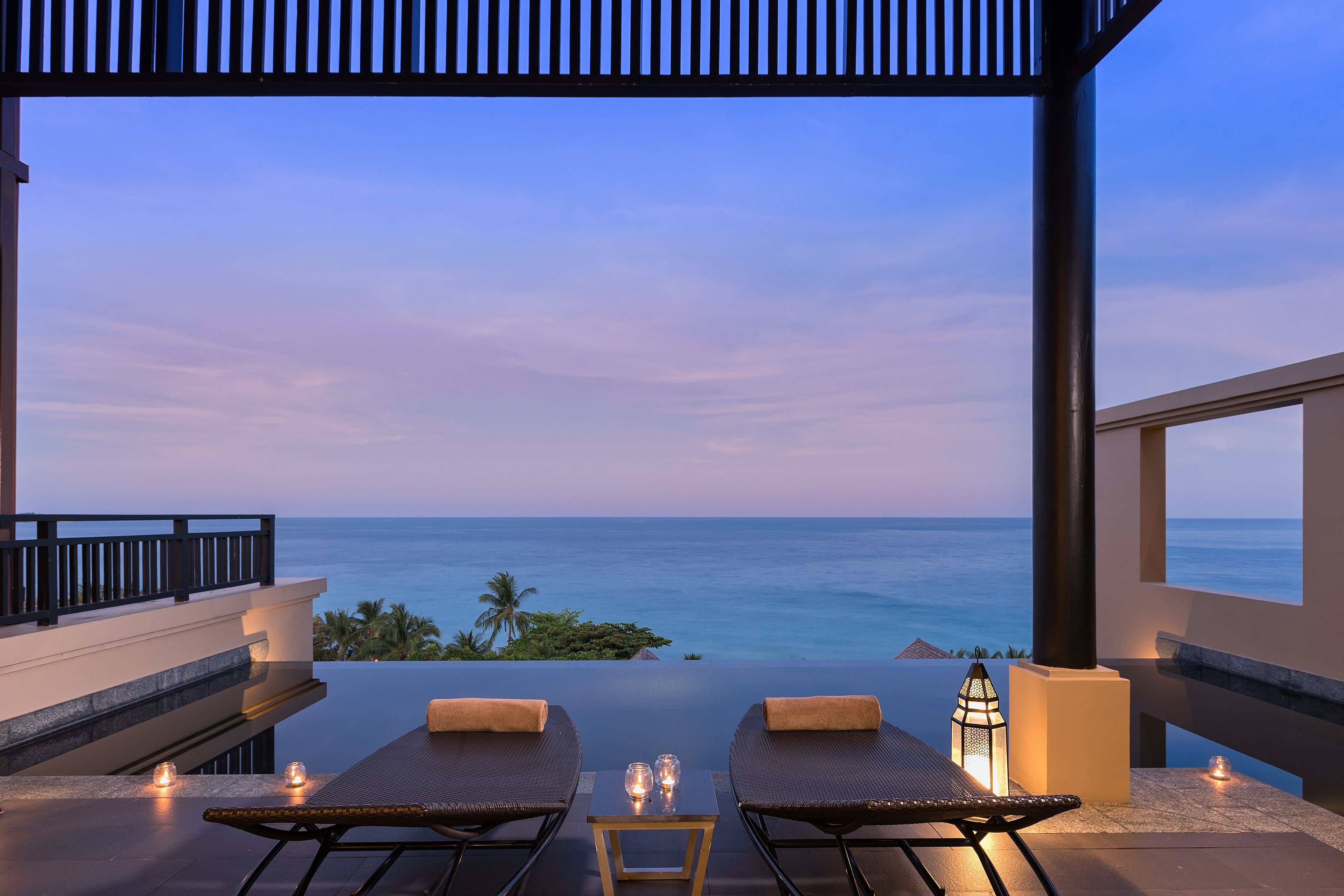 Un balcon avec deux fauteuils et une table, donnant sur l’océan.