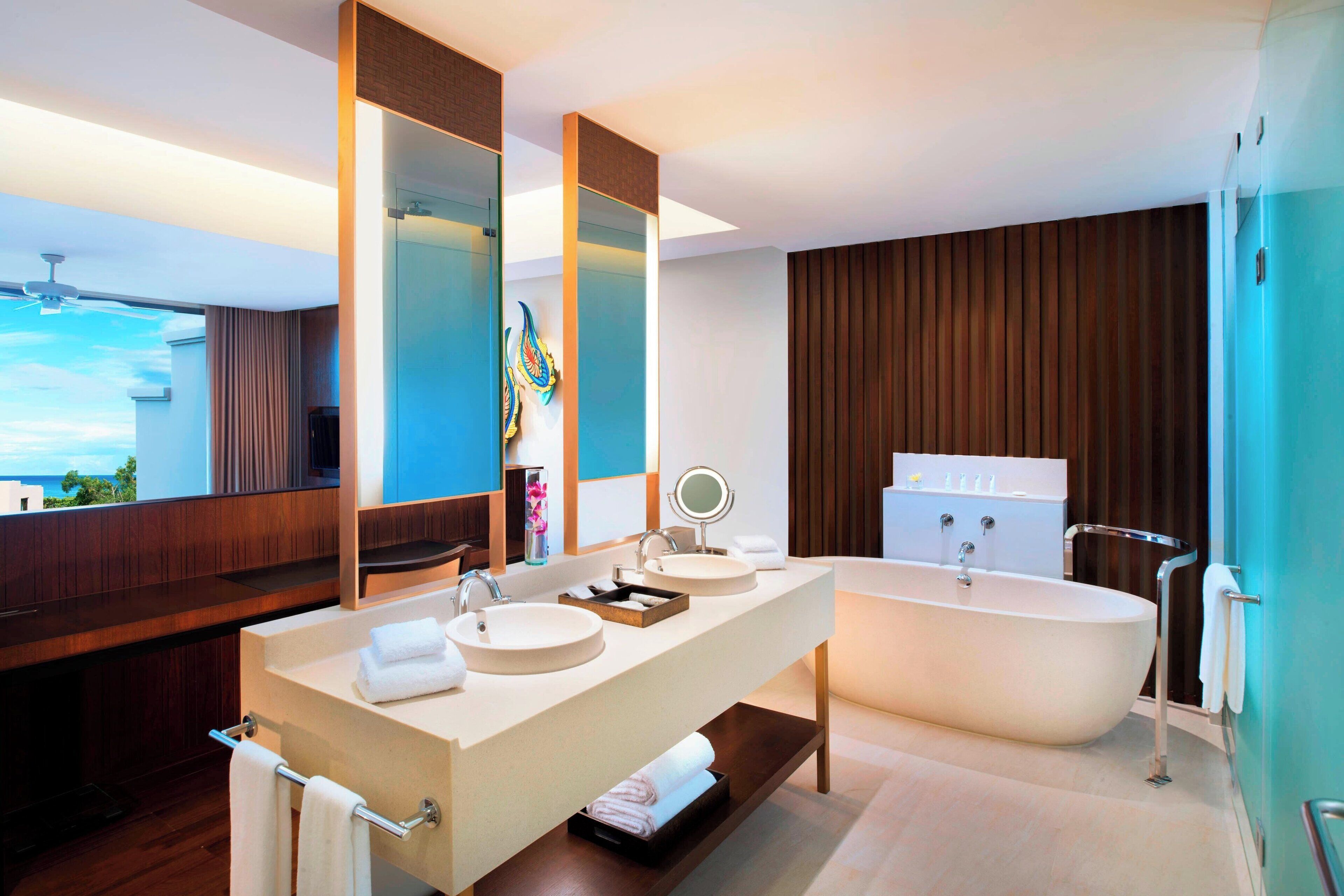 Un baño moderno con un tocador grande, dos lavamanos, una bañera y un espejo amplio.