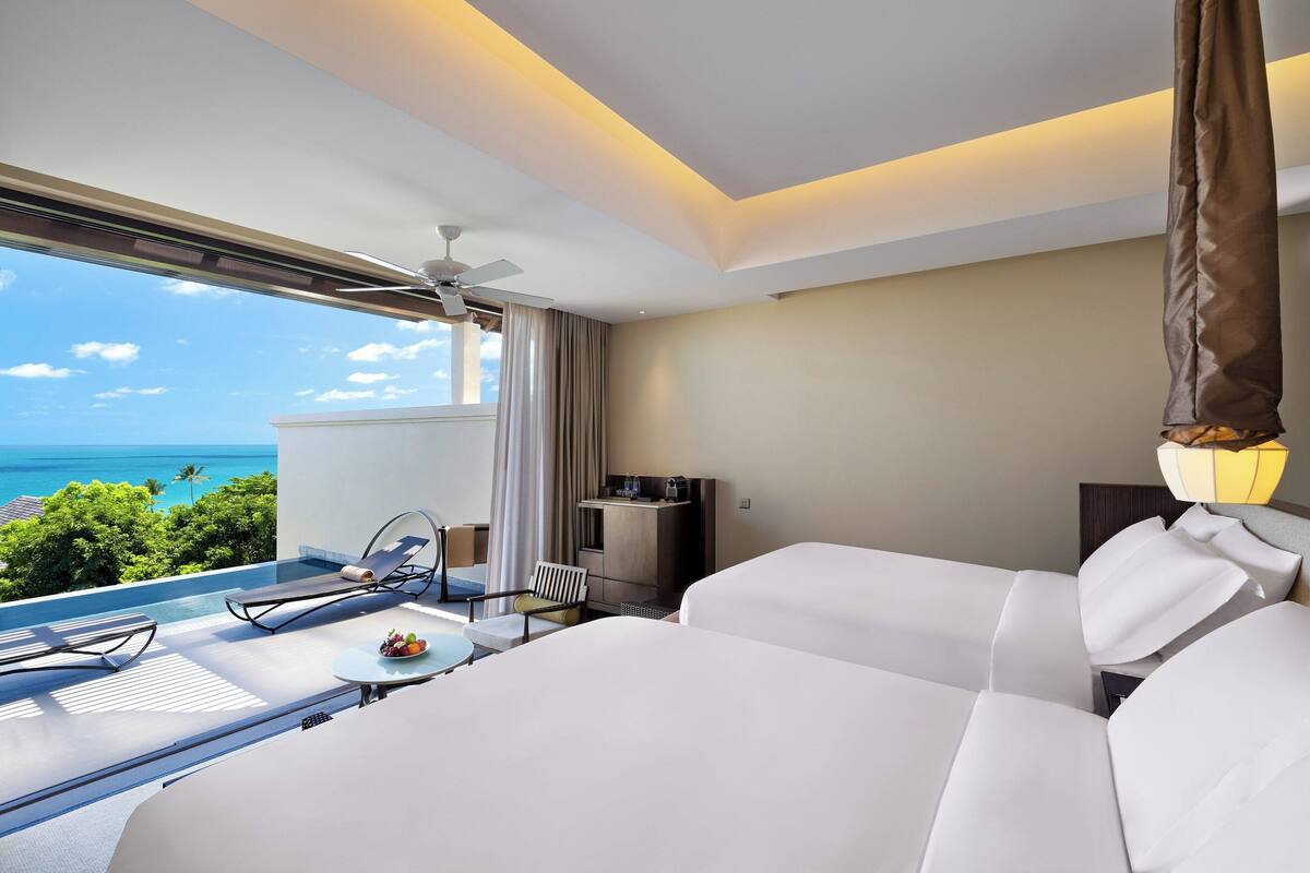A hotel room with a balcony, a bed, a desk, and a chair.
