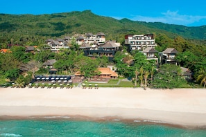 Ein Resort mit mehreren Gebäuden, einem Strand und einer Bergkulisse.
