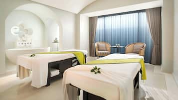 A hotel room with two beds, a bathtub, and a small table with chairs.