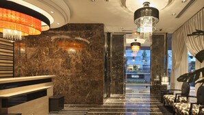 Een statig lobbymede een marmeren trap, een kroonluchter en uitzicht op het hotelgebouw.
