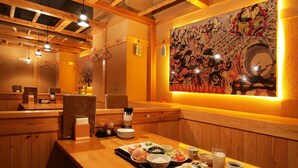 Een restaurant met houten inrichting, een grote muurschildering en diverse gerechten op tafel.