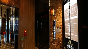 Een hotel lobby met een marmeren vloer, een houten receptiebalie en een digitaal overzicht met informatie over de kamers.