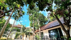 A residential area with a house featuring a tiled roof, a staircase, and a small garden area with palm trees. - ASTROCOCO beach resort by Coconut Beach (Koh Samui)