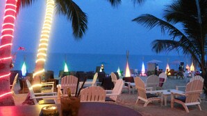 A beachside seating area with chairs and tables, palm trees, and a view of the ocean. - ASTROCOCO beach resort by Coconut Beach (Koh Samui)