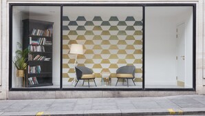 Un interno moderno con una libreria, due poltrone e una parete decorata da un motivo.