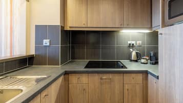 A modern kitchen with wooden cabinets, a black countertop, and a built-in stove.