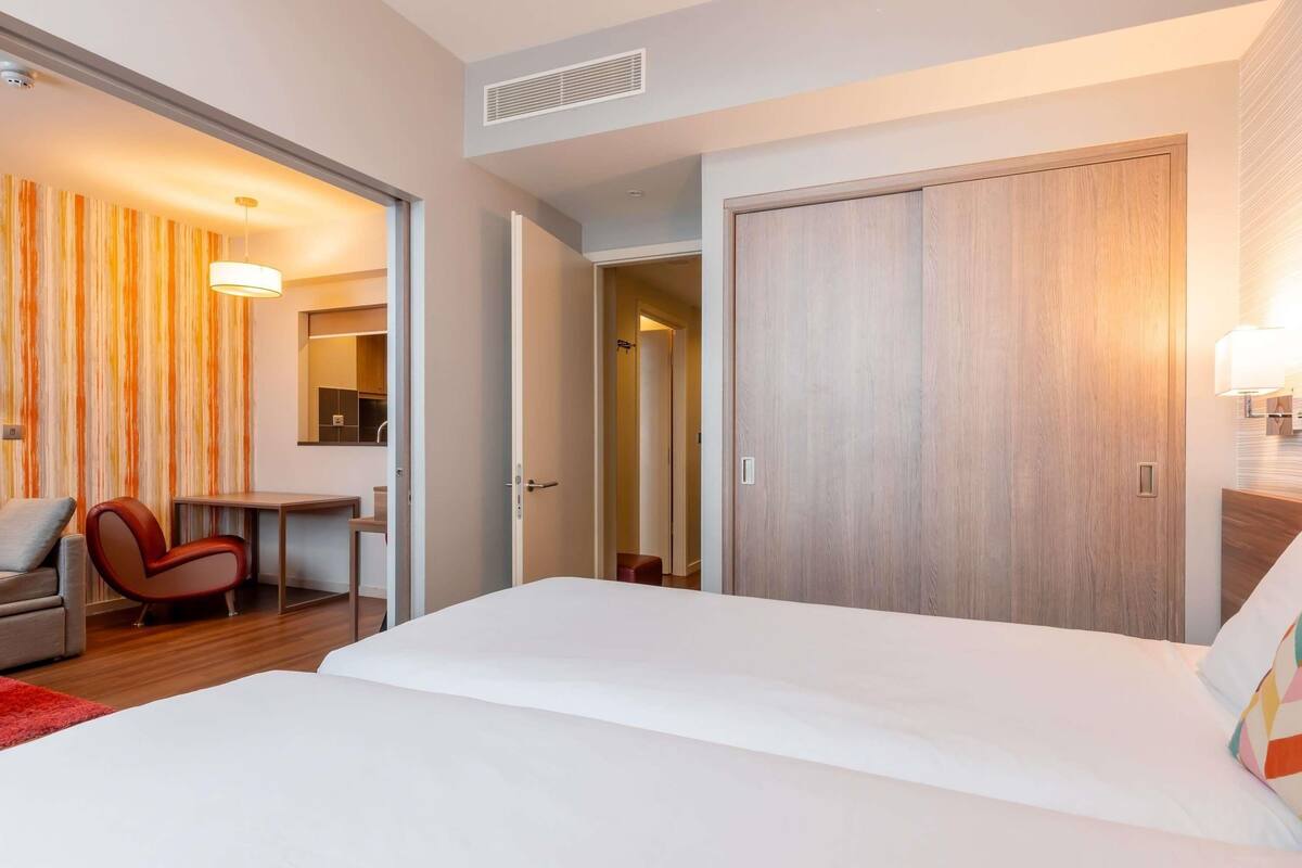 Une chambre d’hôtel avec un lit, un bureau, une chaise et une armoire.
