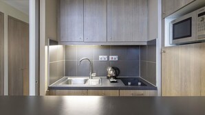 Una cucina moderna con mobili grigi, un lavello in acciaio inossidabile e un forno a microonde Bosch.