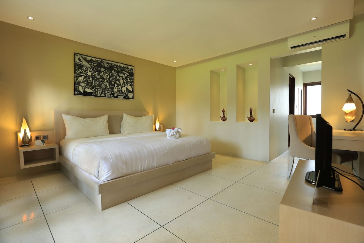 A modern hotel room with a large bed, bedside tables, a desk, and a chair.