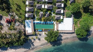 An aerial view of a resort with a swimming pool, beach, and multiple bungalow-style accommodations. - Living Asia Resort & Spa (Senggigi)