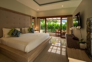 Quarto moderno com uma cama grande, uma televisão e vista para o verde lá fora.