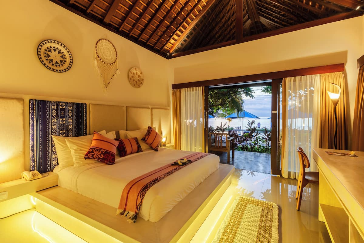 A spacious bedroom with a large bed, a wooden ceiling, and a view of the outdoors.