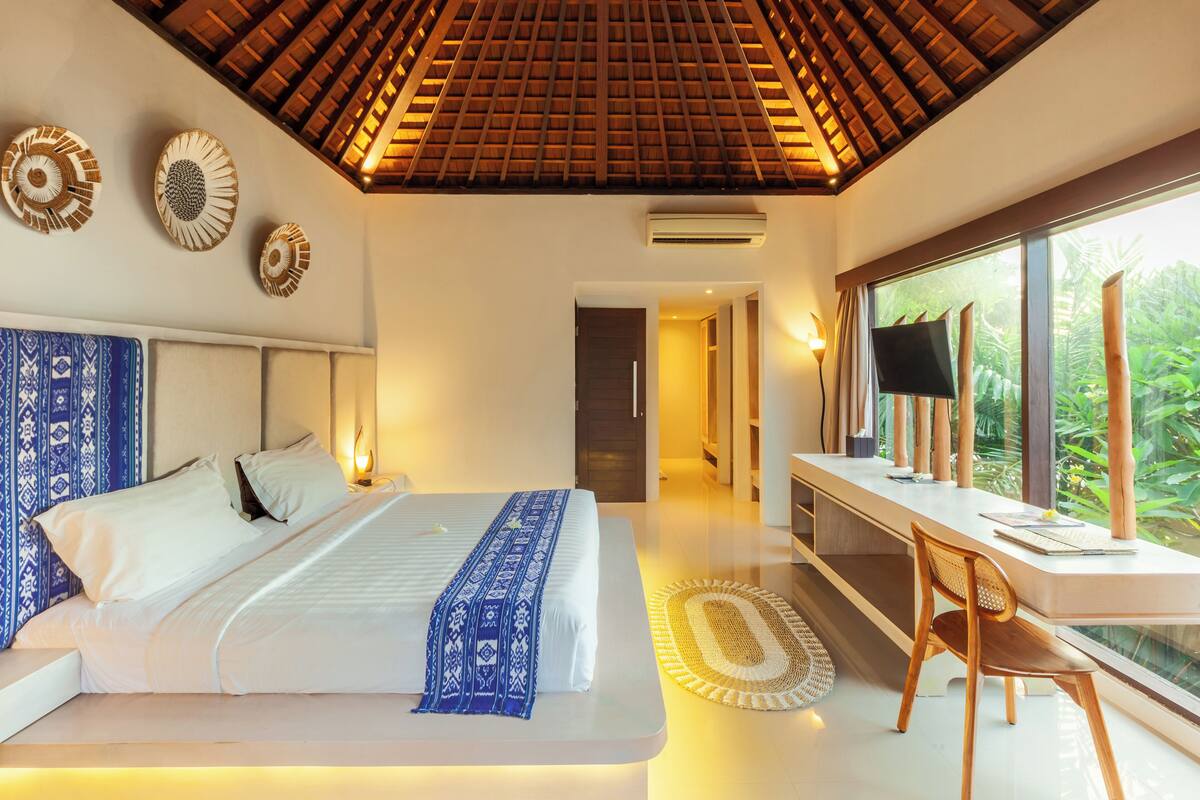 A modern bedroom with a large bed, a desk, and a TV.