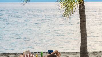 On the beach, black sand, sun-loungers, beach umbrellas