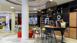 A modern interior with a central table, chairs, hanging lamps, and a large black wall with text. - Aparthotel Adagio Köln City (Cologne)