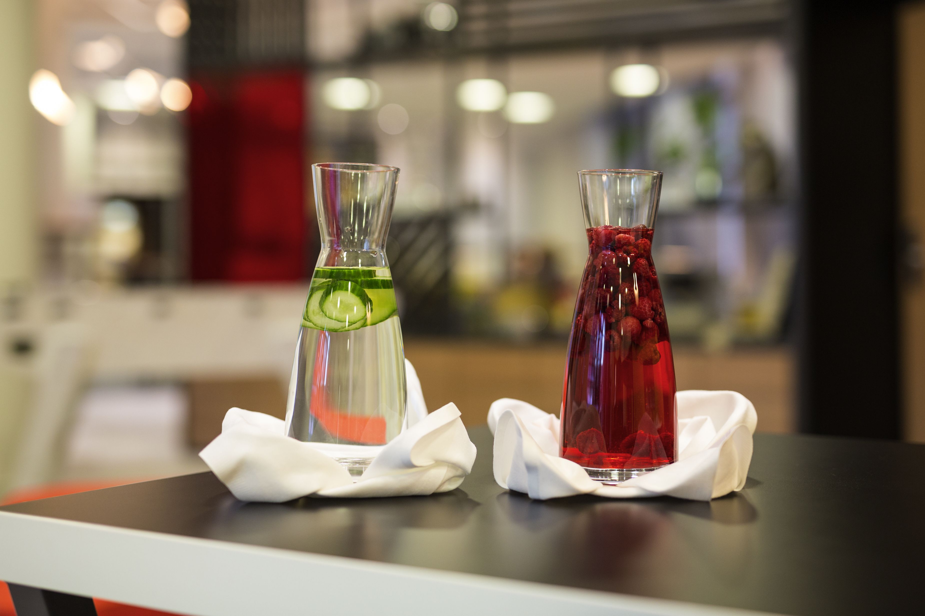 Two glass bottles with different colored liquids on a table, each with a white napkin.