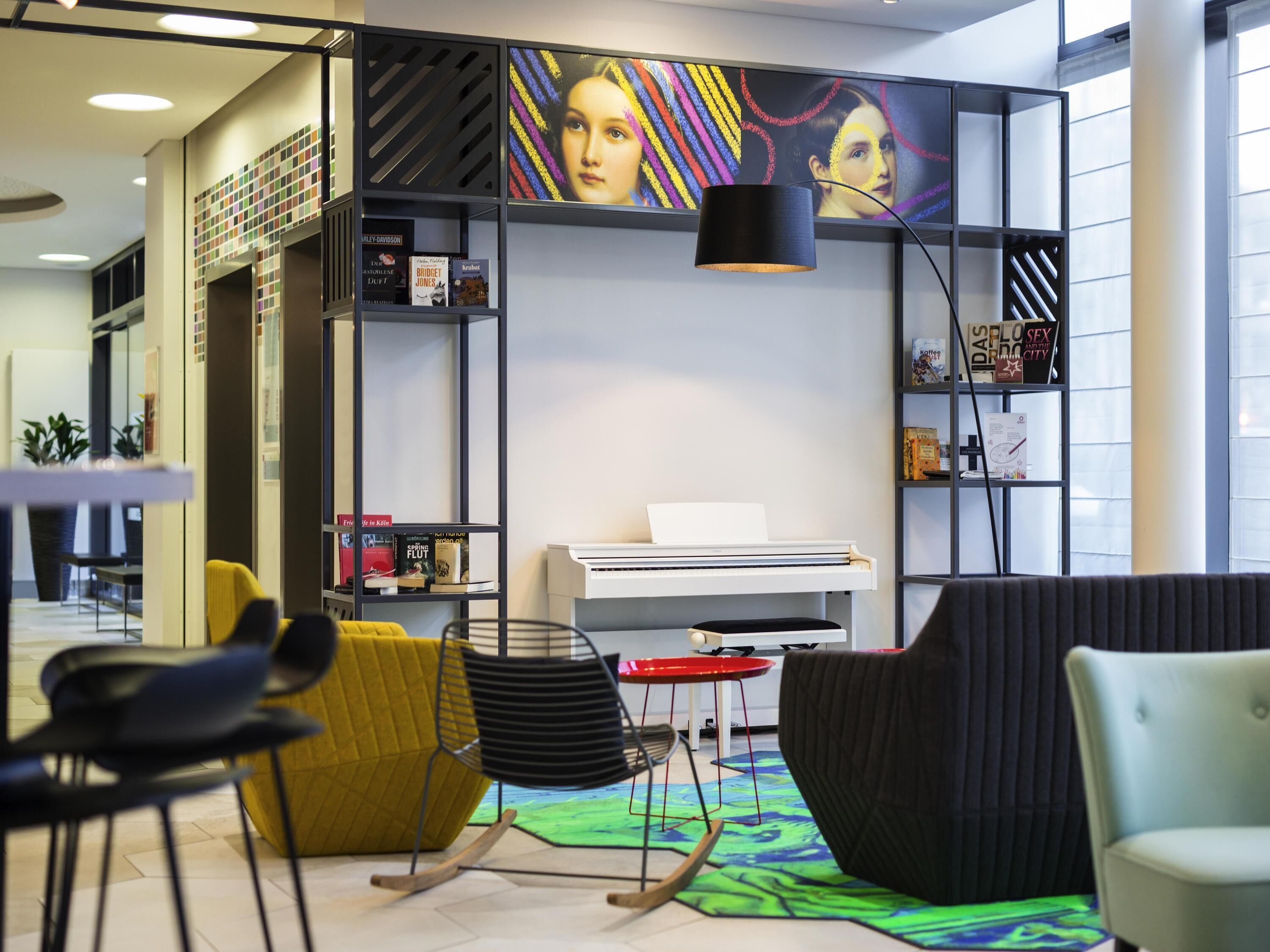A modern reading area with a piano, bookshelves, and comfortable seating.