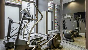 A gym with cardio machines, mirrors, and a patterned wall.