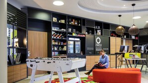 A modern interior with a foosball table, a sofa, and a desk with a computer. - Aparthotel Adagio Köln City (Cologne)