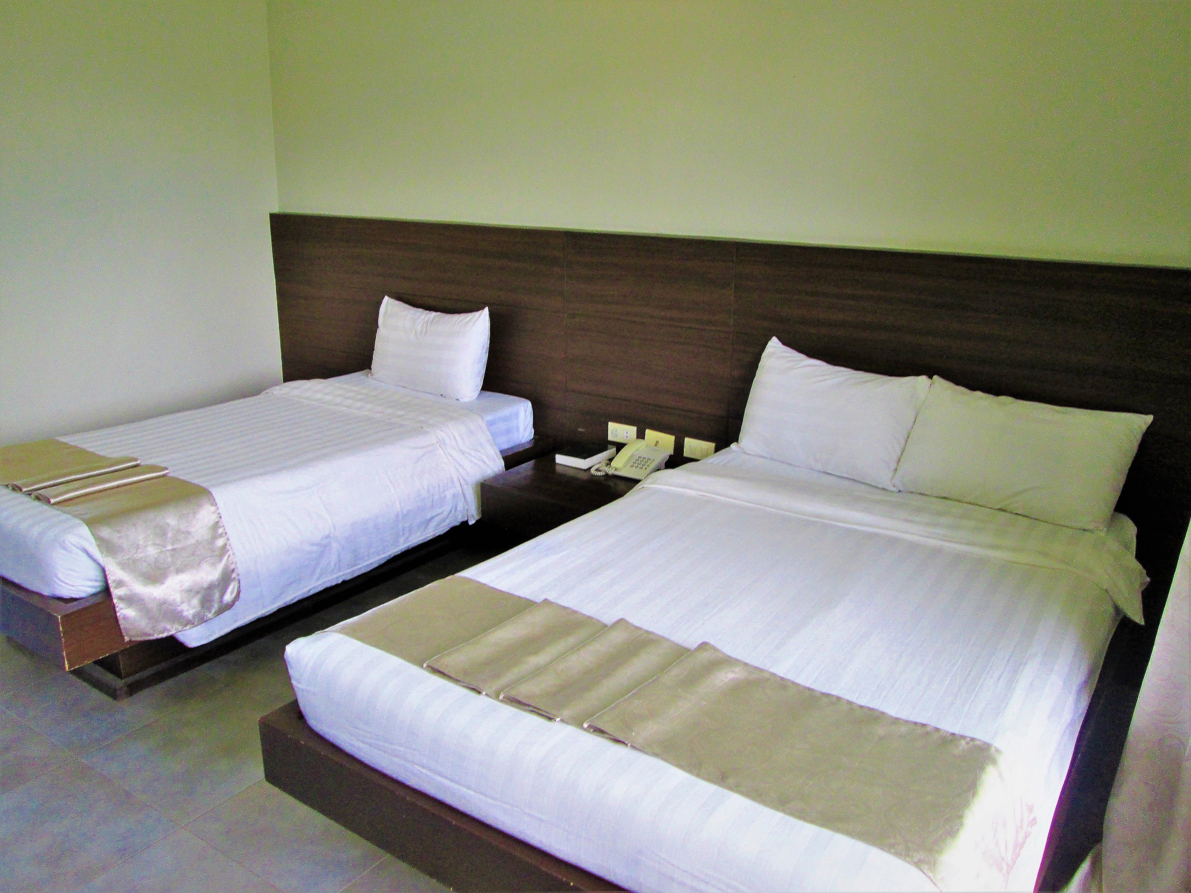 Dos camas individuales con cabeceras de madera, ropa blanca de cama y un teléfono junto a la cama.