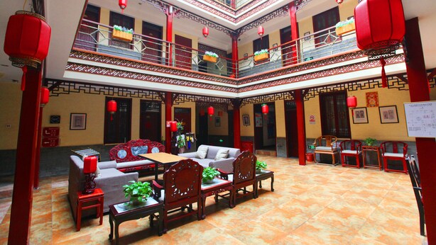 Un patio tradicional de varios niveles con una zona de estar central, faroles rojos y suelo de baldosas.