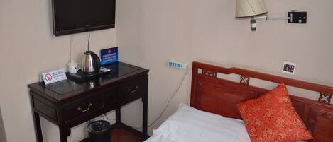 Une chambre d’hôtel équipée d’un lit, d’un bureau avec une télévision, d’une lampe et d’un panneau indiquant qu’il est interdit de fumer.
