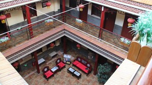 Un patio tradicional al estilo chino con barandillas de patrones rojos y blancos, muebles de madera y faroles colgantes.
