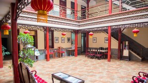 Un patio tradicional chino con faroles rojos, muebles de madera y una escalera.
