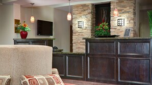A modern kitchen with a stone accent wall, a flat-screen TV, and a bar area with a large wooden cabinet. - Best Western Plus Cushing Inn & Suites (Cushing)