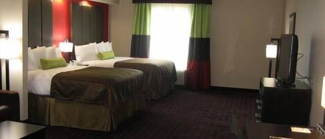 Quarto de hotel com duas camas, uma escrivaninha, uma televisão e uma janela com cortinas.