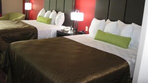 A hotel room with two beds, each with white bedding and green pillows, a red accent wall, and bedside lamps. - Best Western Plus Cushing Inn & Suites (Cushing)