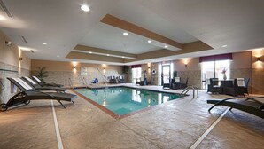 A swimming pool with lounge chairs, a sunbed, and a table with chairs. - Best Western Plus Cushing Inn & Suites (Cushing)