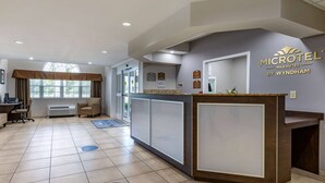 A reception area with a reception desk, a large window with curtains, and a sign for 'MICROTEL INN & SUITES BY WYNDHAM'. - Microtel Inn & Suites By Wyndham Sylva Dillsboro Area (Sylva)