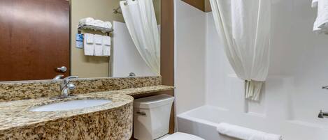Ein Badezimmer mit Granitwaschtisch, Toilette, Badewanne und Duschvorhang.