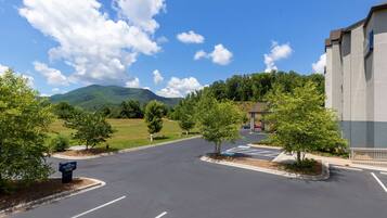 A parking lot with a hotel sign, trees, and a mountain in the background.