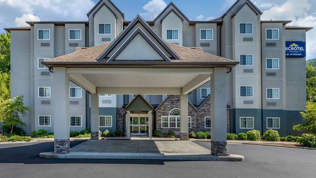 A micro hotel with a covered entrance, multiple floors, and a sign indicating it is by Wyndham. - Microtel Inn & Suites By Wyndham Sylva Dillsboro Area (Sylva)