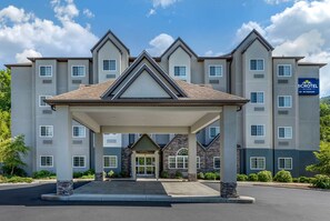 A micro hotel with a covered entrance, multiple floors, and a sign indicating it is by Wyndham. - Microtel Inn & Suites By Wyndham Sylva Dillsboro Area (Sylva)
