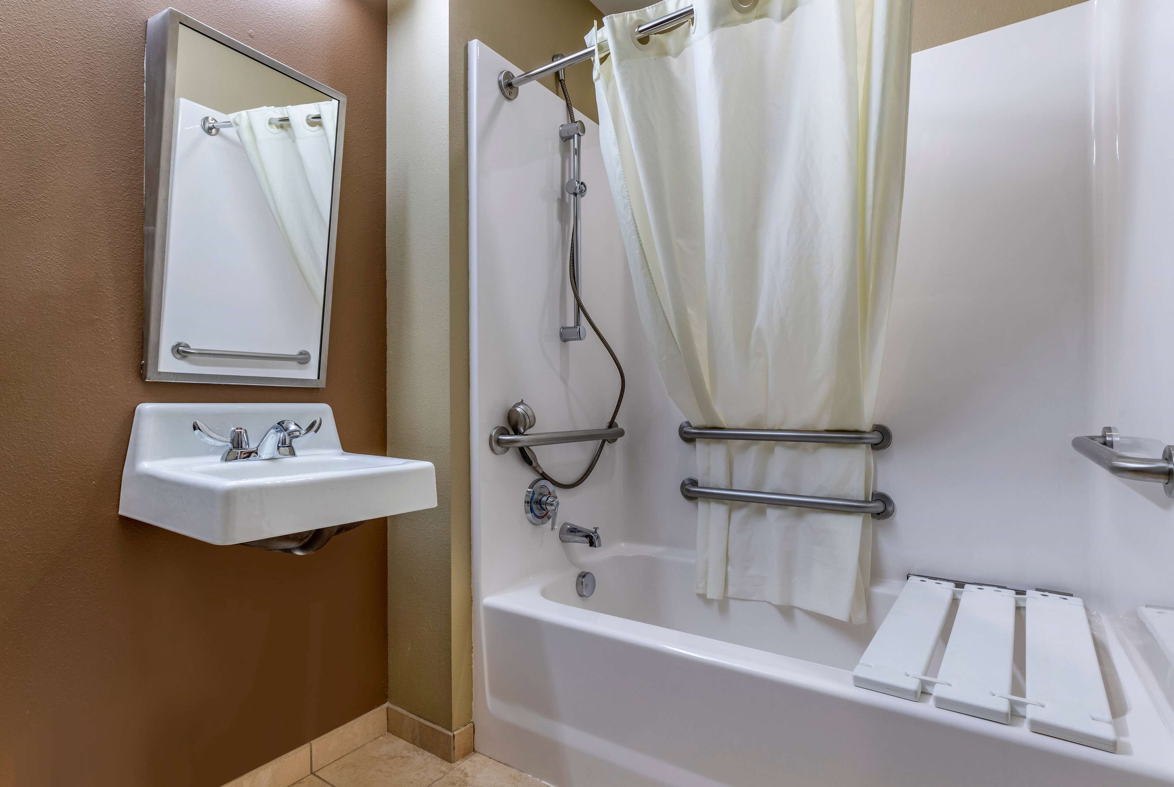 A bathroom with a white sink, a mirror, a bathtub with a shower curtain, and a towel rack.