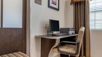 Et moderne kontor med skrivebord, computer, stol og et billede i ramme på væggen.