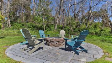 A circular outdoor seating area with Adirondack chairs and a stone fire pit.