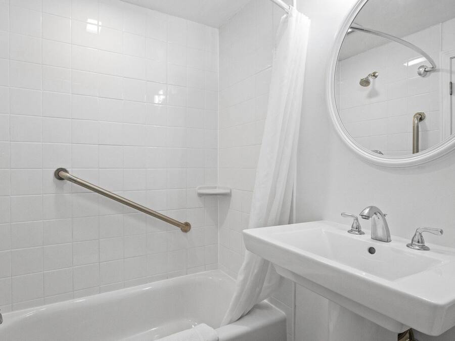 A bathroom with a white bathtub, a sink with two faucets, and a shower area with a glass door.