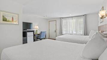 Habitación de hotel con dos camas, un escritorio con silla, televisión y un cuadro en la pared.