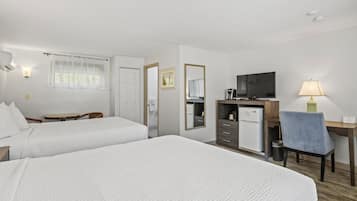 Quarto de hotel com duas camas, uma escrivaninha, uma televisão e uma cadeira.