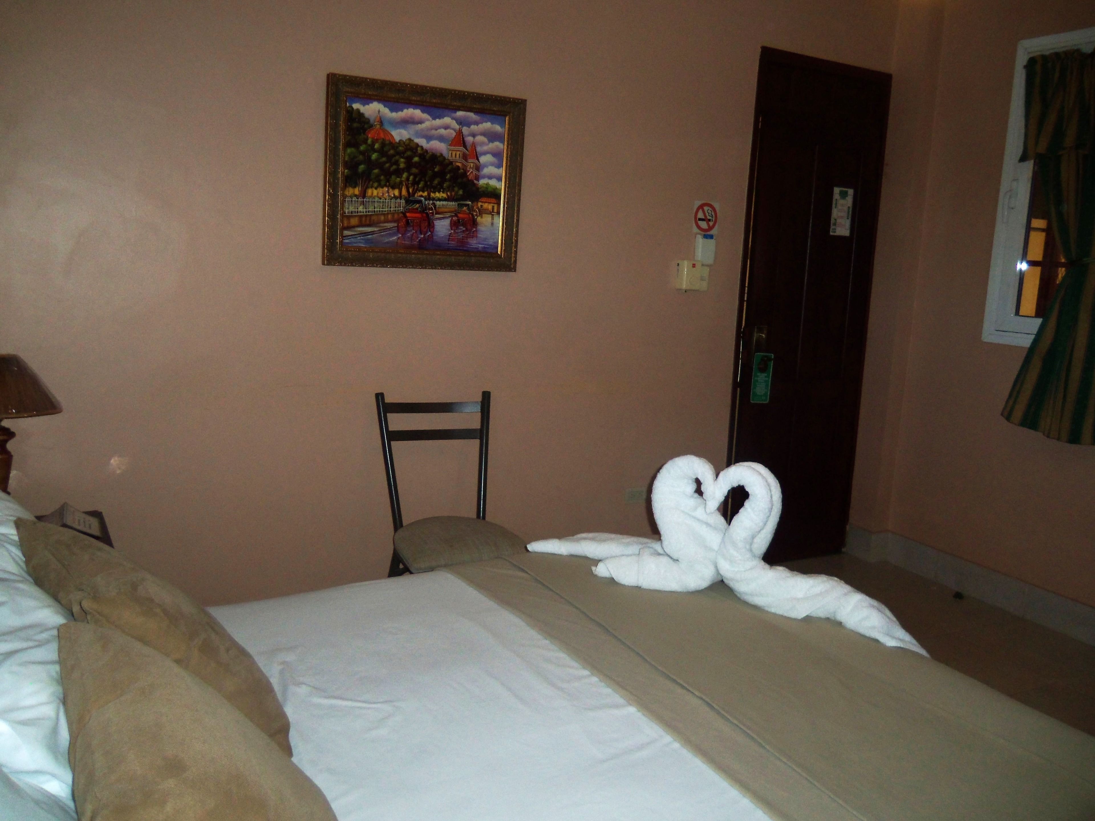 Une chambre d’hôtel avec un lit, une chaise, un tableau au mur et une porte.