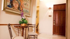 A dining area with a table, chairs, a potted plant, and a painting on the wall. - Hotel Discovery (Santo Domingo)