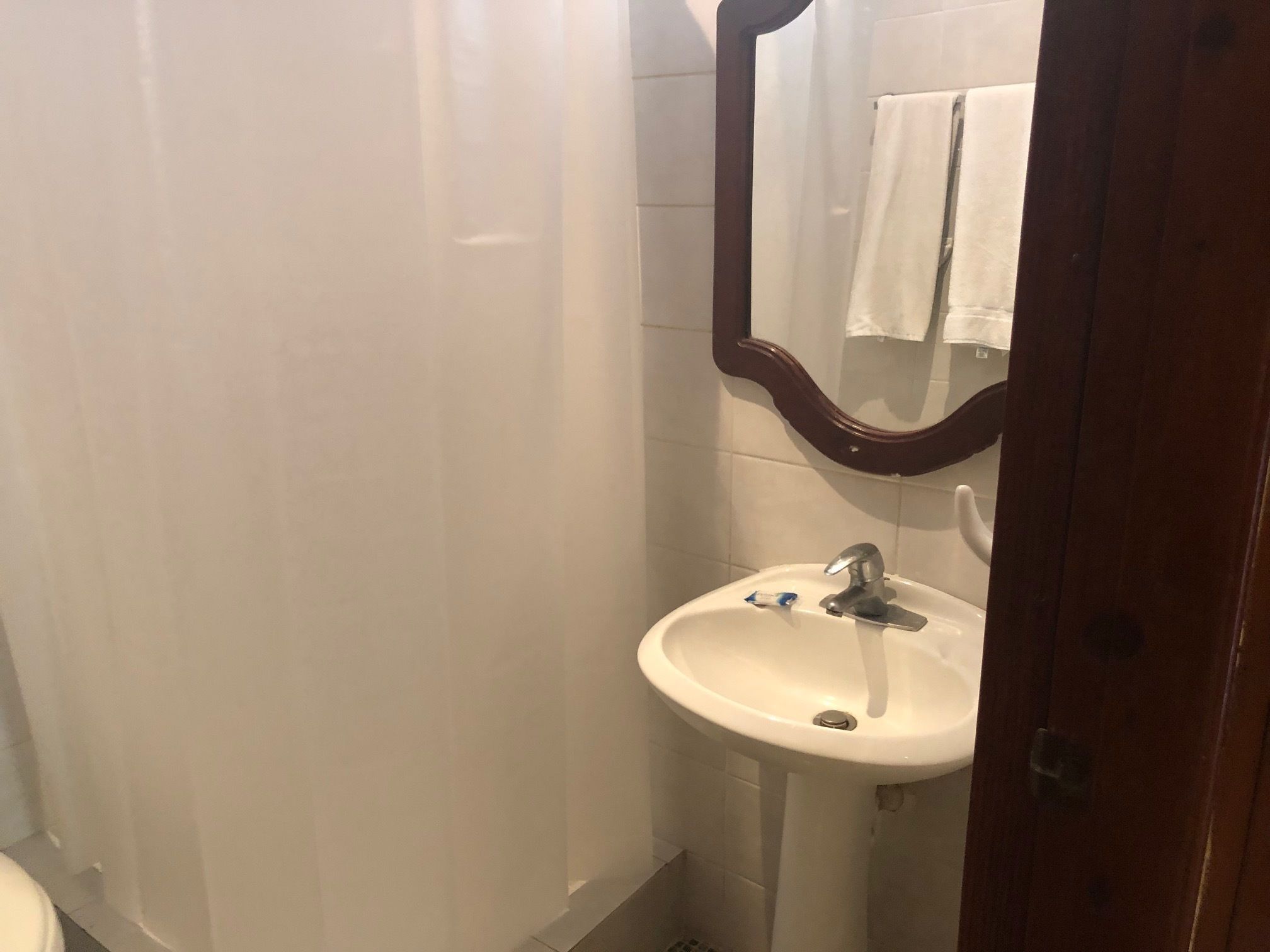 A bathroom with a white sink, a mirror, and a shower curtain.